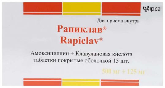 На фото таблетки покрытые оболочкой Рапиклав, Амоксициллин + Клавулановая кислота, в количестве 15 шт.
